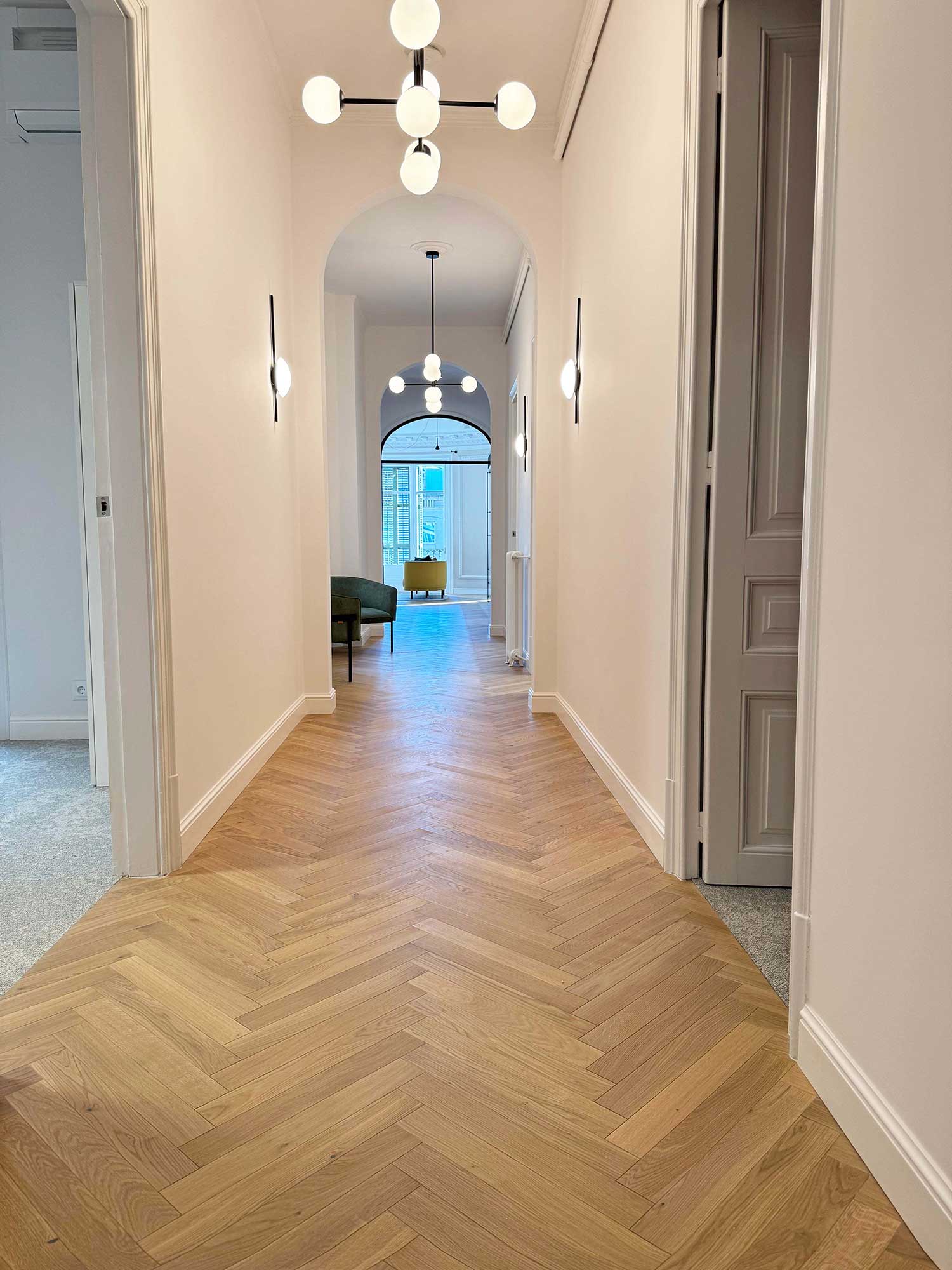 Pasillo con arcos y parquet en espiga instalado por WINco en unas oficinas de finca regia en el Eixample.