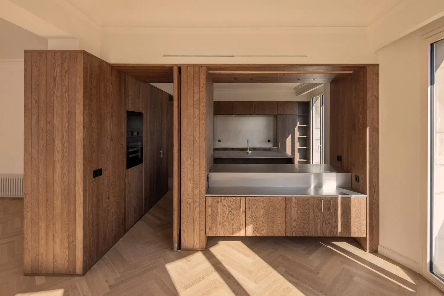 Continuidad del parquet en espiga entre estancias en una vivienda reformada de Barcelona