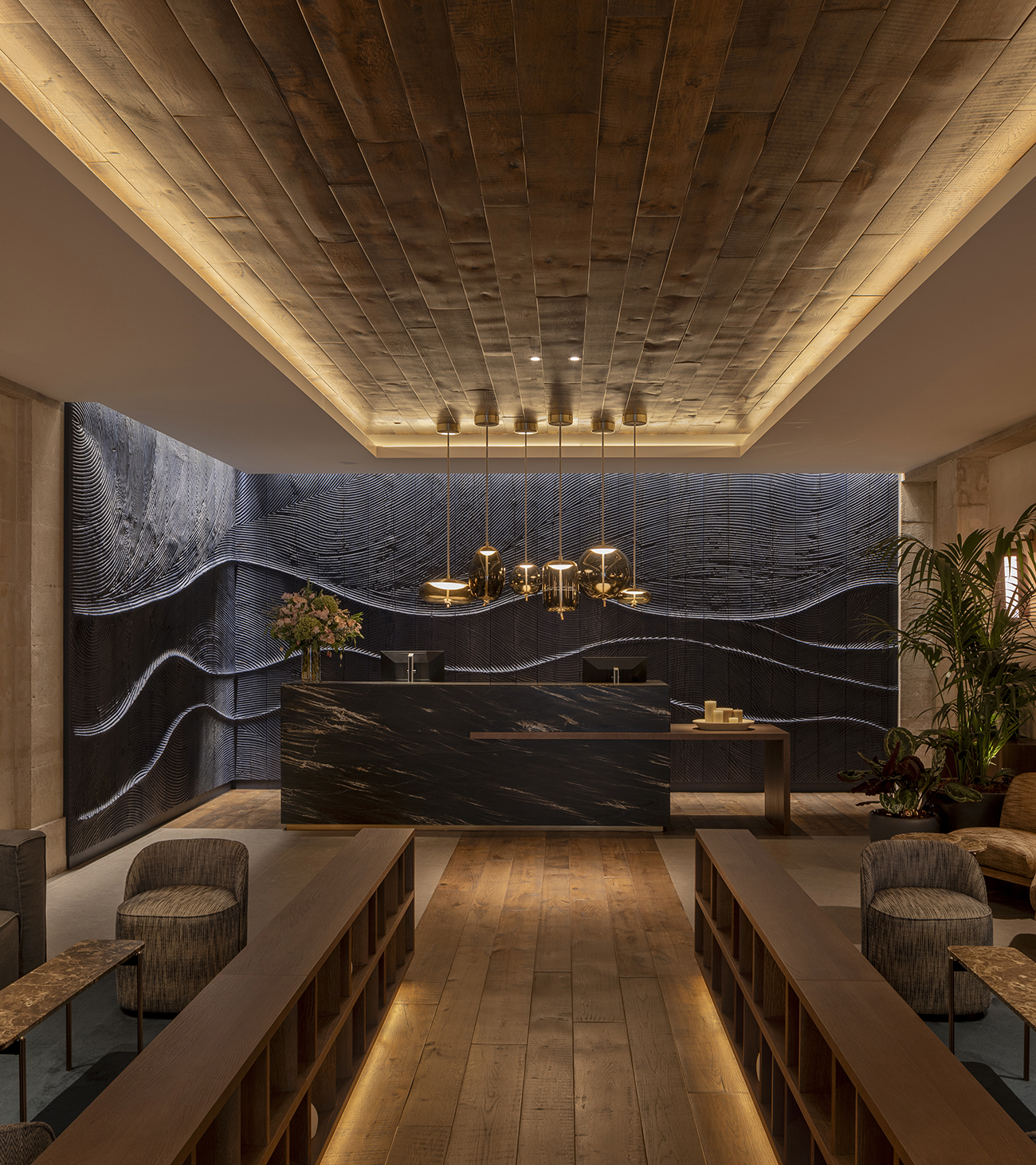 Lobby del Hotel Medinaceli con revestimiento de madera, recepción y mural ondulado con iluminación cálida