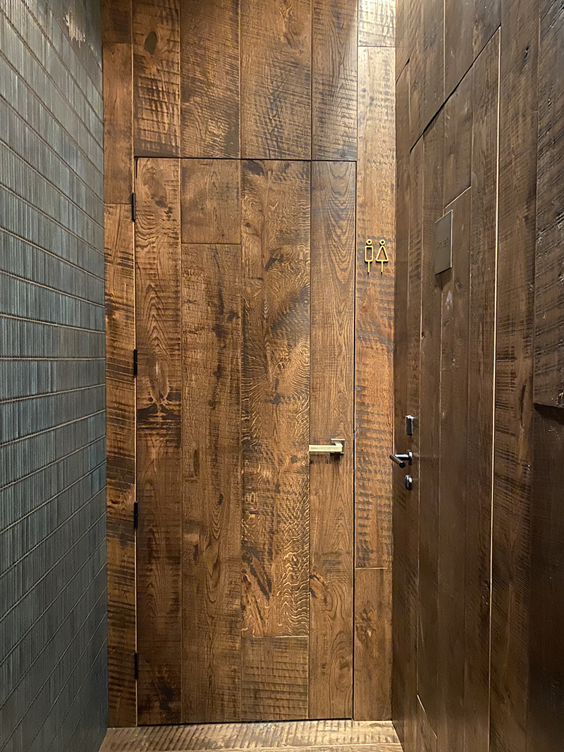 Puertas integradas en madera con continuidad de parquet en el Chapter 8, instalación profesional por WINco.