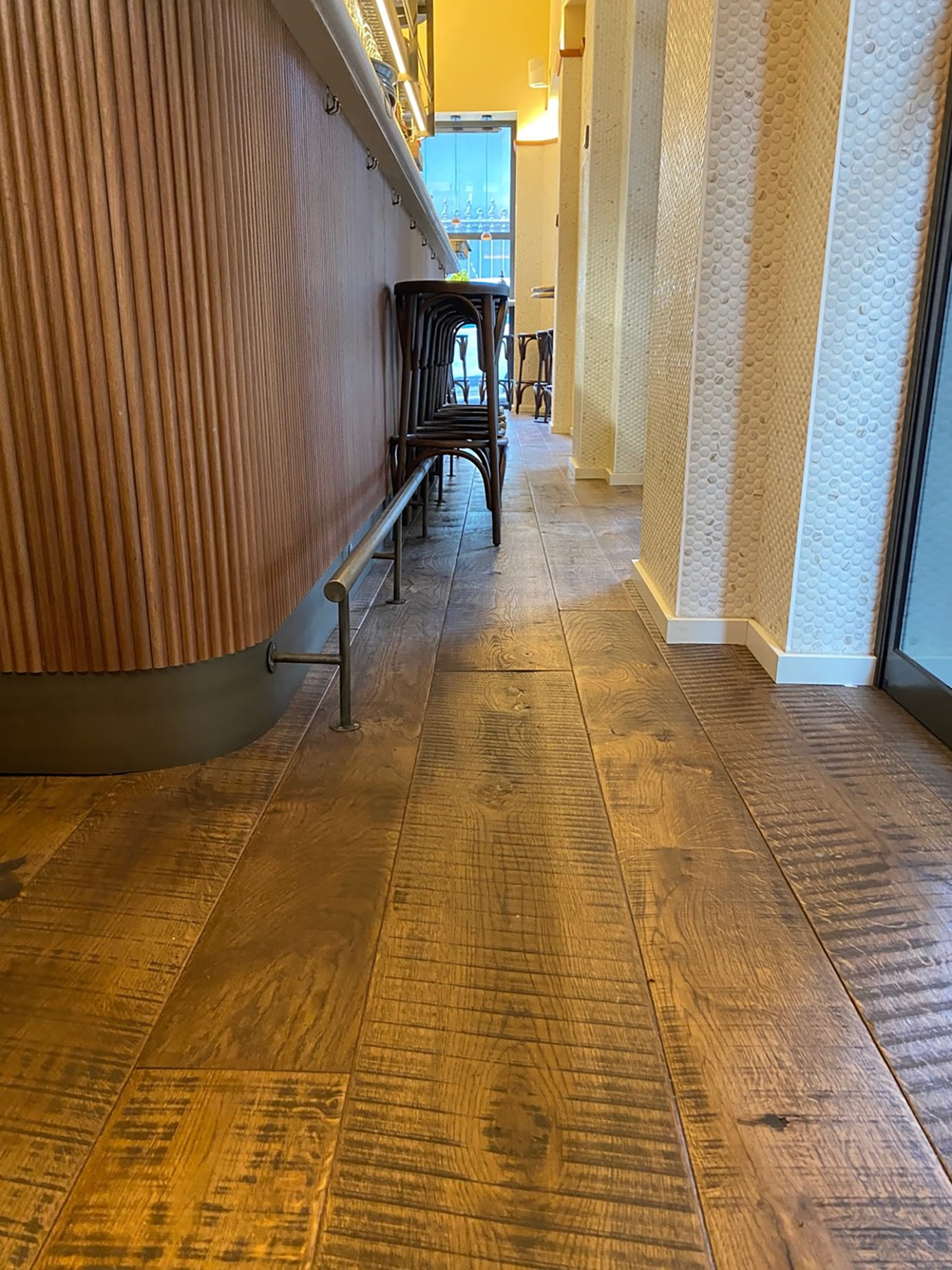 Pasillo interior de Barra Cal Pla con el suelo de madera de aspecto recuperado junto a la barra Pasillo interior de Barra Cal Pla con el suelo de madera de aspecto recuperado junto a la barra